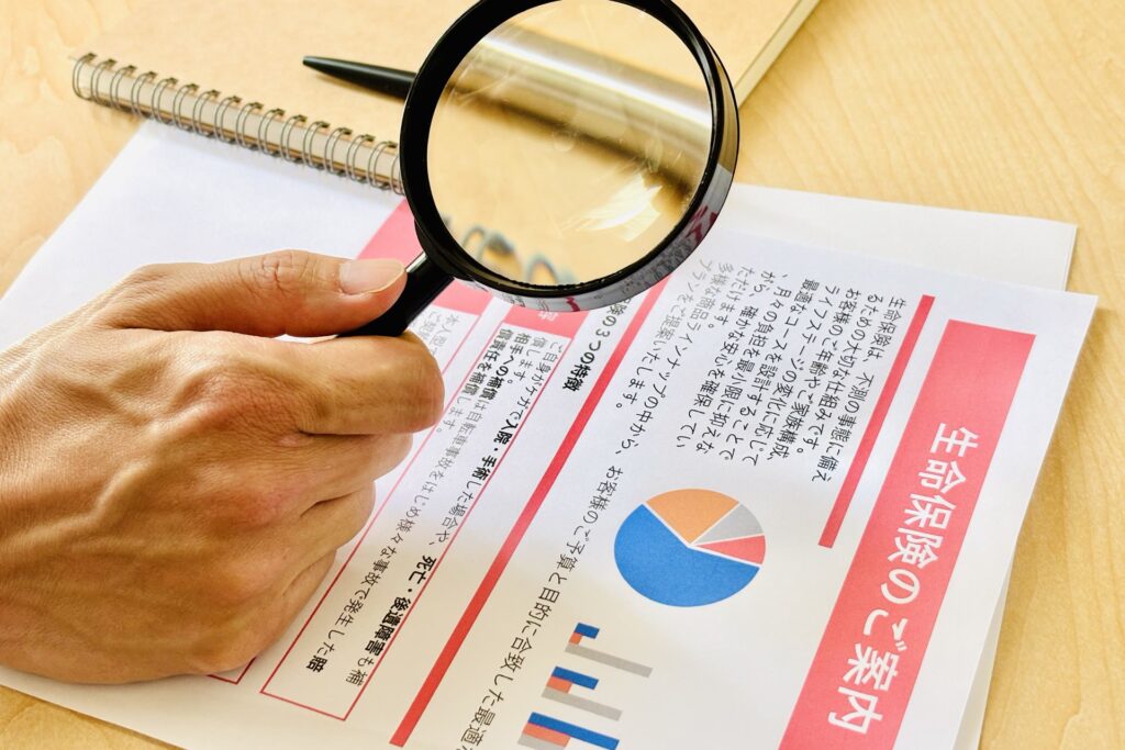 生命保険の案内資料虫眼鏡で確認する