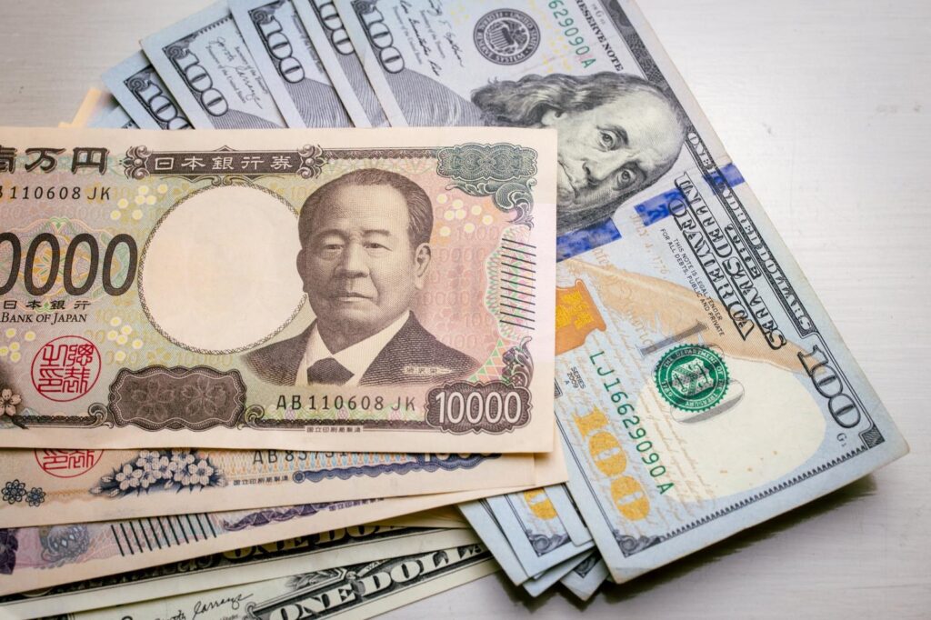 テーブルの上に重なった一万円札と米ドル紙幣