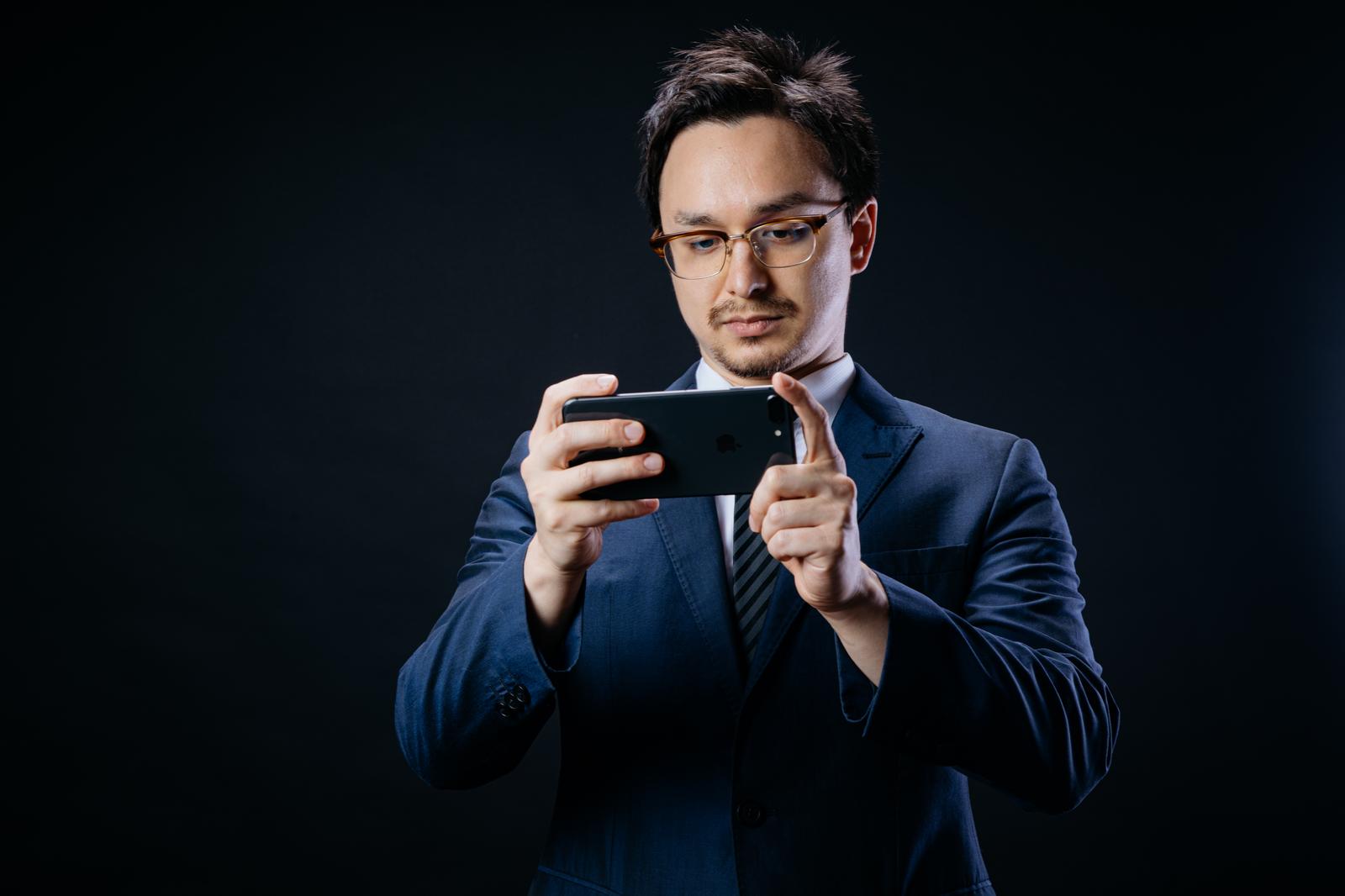 横向きのスマホ画面を見るスーツの男性